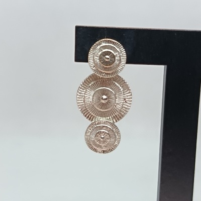 Brinco dourado com três círculos texturizados pendurado em suporte preto