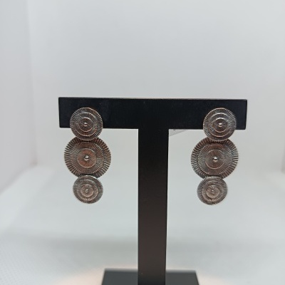 Brincos prateados com três discos texturados em suporte preto.