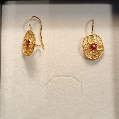 Brincos dourados ovais com flor vermelha no centro em caixa de tecido branco