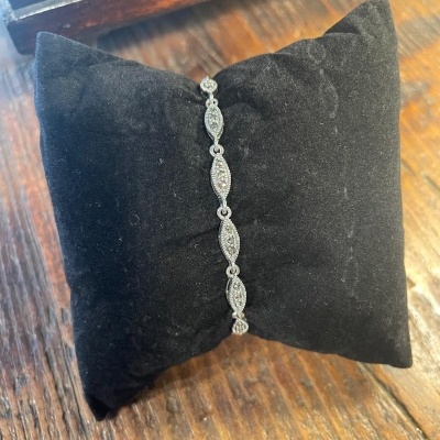 Pulseira prateada com pedras sobre almofada preta