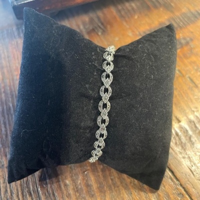 Pulseira brilhante em almofada preta sobre mesa de madeira