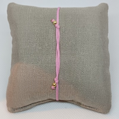 Almofada bege texturada com pulseira rosa fina e detalhes dourados