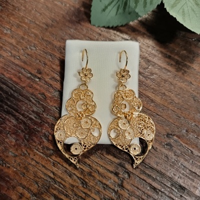 Brincos dourados em filigrana com padrão circular e floral sobre tecido branco