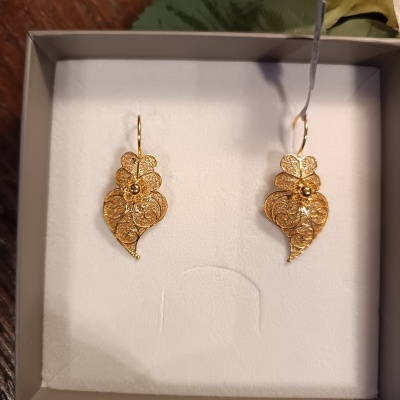 Par de brincos dourados em caixa branca.