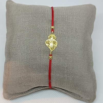 Pulseira vermelha com pendente dourado em almofada cinza texturada