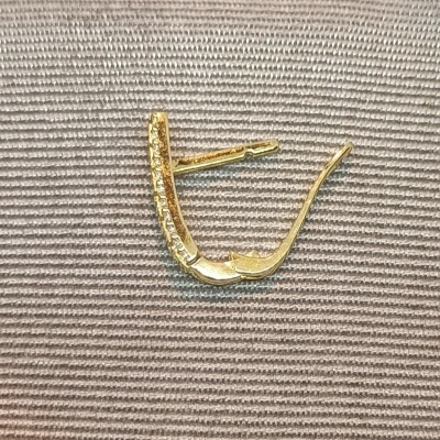 Brinco dourado com pedras brilhantes sobre tecido cinza