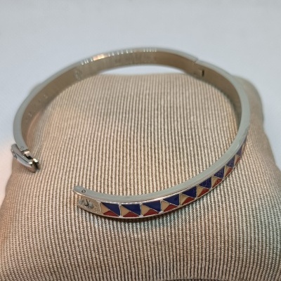 pulseira metálica prateada com padrão colorido sobre almofada bege