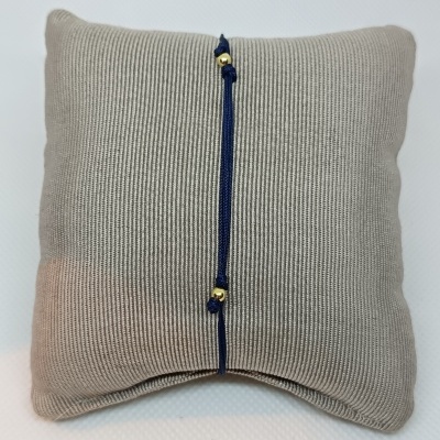 Pulseira azul escuro com contas douradas sobre almofada cinzenta