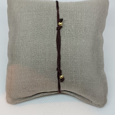 Almofada cinzenta com cordão castanho e elementos dourados