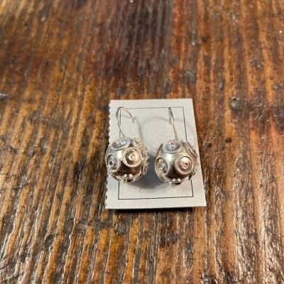 brincos pendentes em metal prateado com detalhes texturados e esferas decorativas