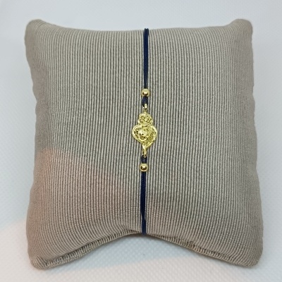 Pulseira azul com coração dourado sobre almofada cinza
