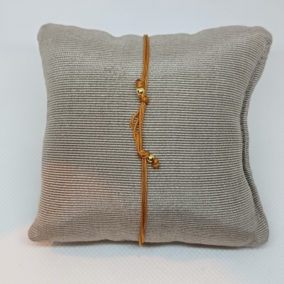 Almofada cinza com pulseira dourada sobre fundo branco