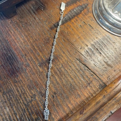 Pulseira prateada detalhada sobre mesa de madeira