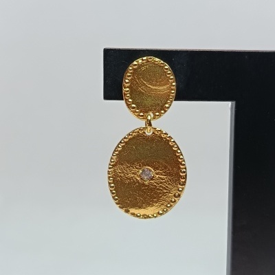 Brinco dourado pendente com pedras e textura em suporte preto