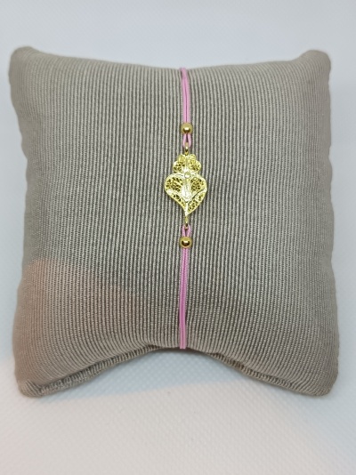 Pulseira com fio rosa e detalhe em forma de coração dourado sobre almofada cinzenta