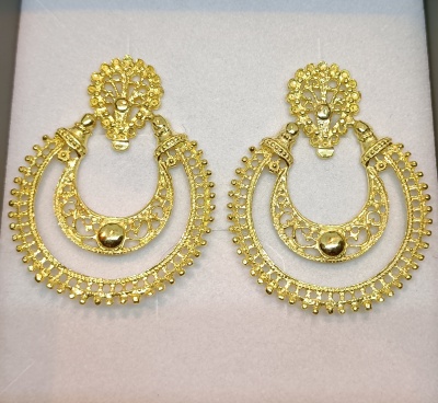 Brincos dourados com detalhes em filigrana sobre fundo branco