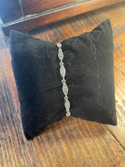 Pulseira prateada com pedras sobre almofada preta