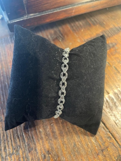 Pulseira brilhante em almofada preta sobre mesa de madeira
