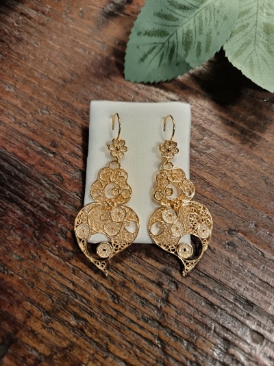 Brincos dourados em filigrana com padrão circular e floral sobre tecido branco