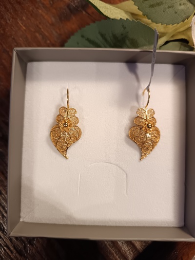 Par de brincos dourados em caixa branca.