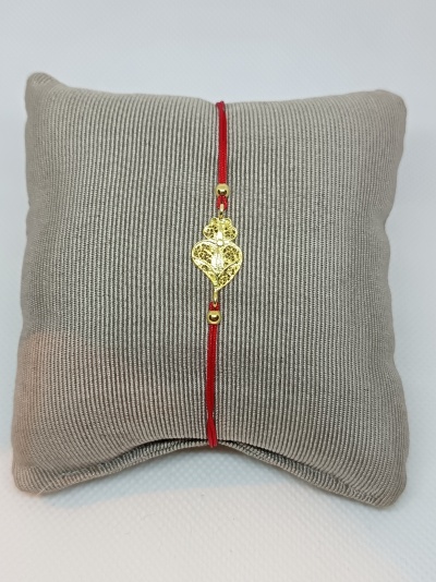 Pulseira vermelha com pendente dourado em almofada cinza texturada