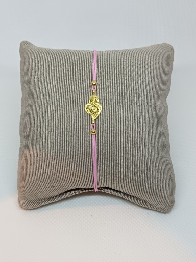 Pulseira com fio rosa e pendente dourado em almofada cinza canelada