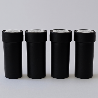 Quatro frascos pretos com tampas e etiquetas brancas no topo, alinhados sobre fundo cinzento.