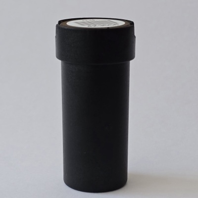 Frasco cilíndrico preto com tampa sobre fundo cinza claro
