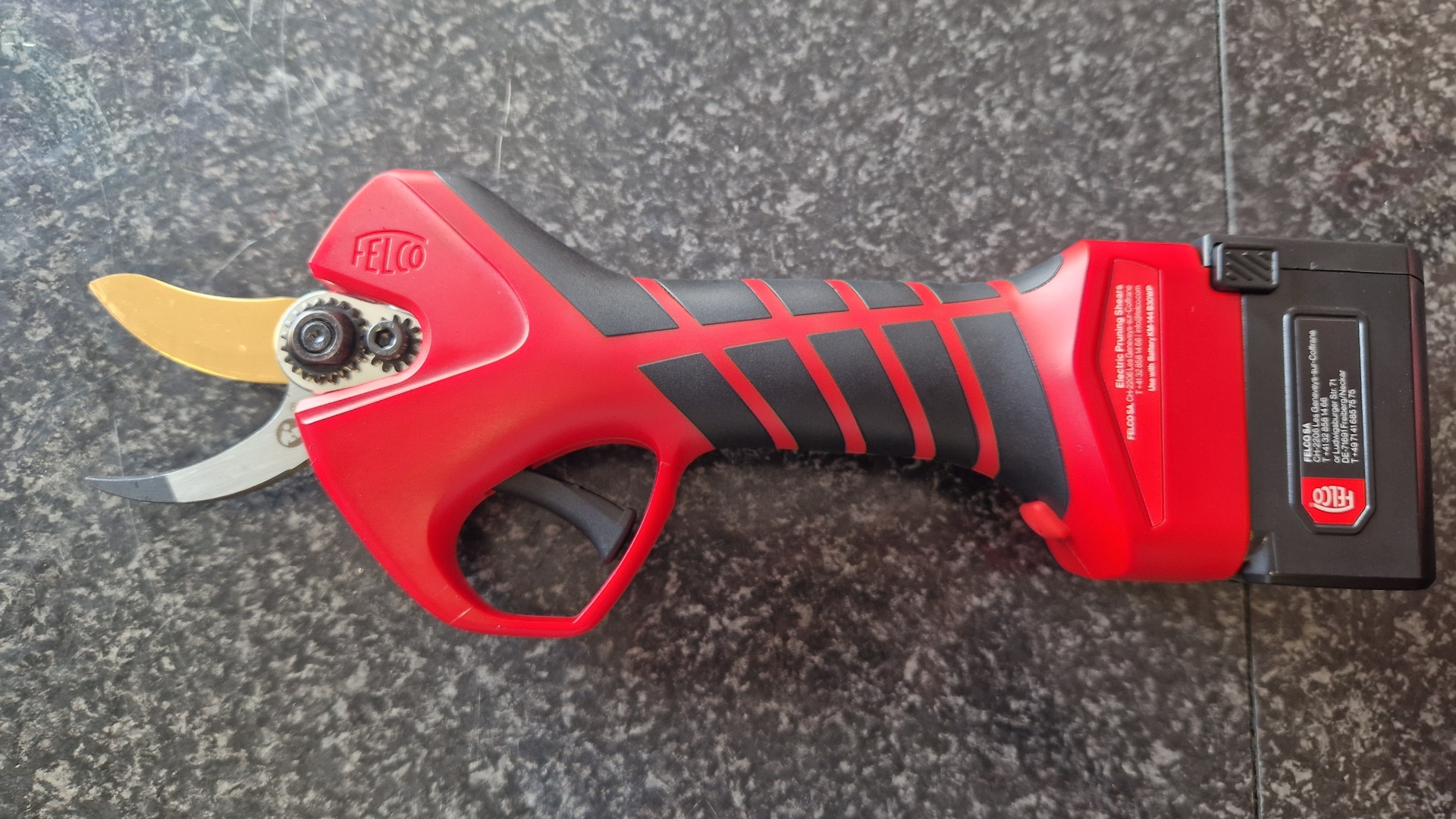 Tesoura de poda elétrica vermelha com detalhes pretos e lâmina metálica