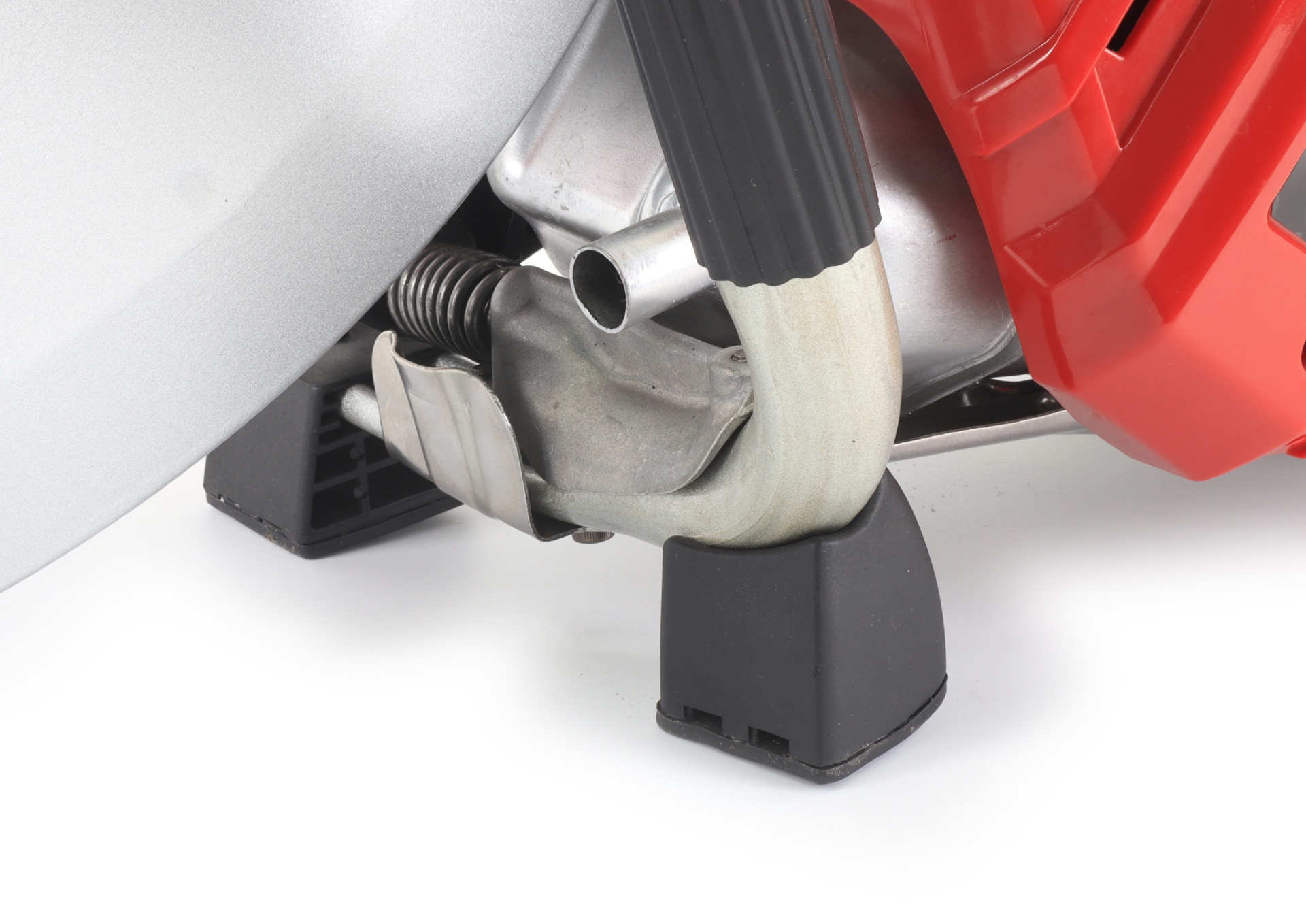 Peça metálica prateada com mola, cabo preto e componente vermelho sobre base preta