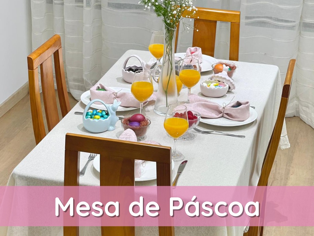 Mesa de jantar decorada para Páscoa com toalha branca, copos com sumo de laranja e ovos coloridos