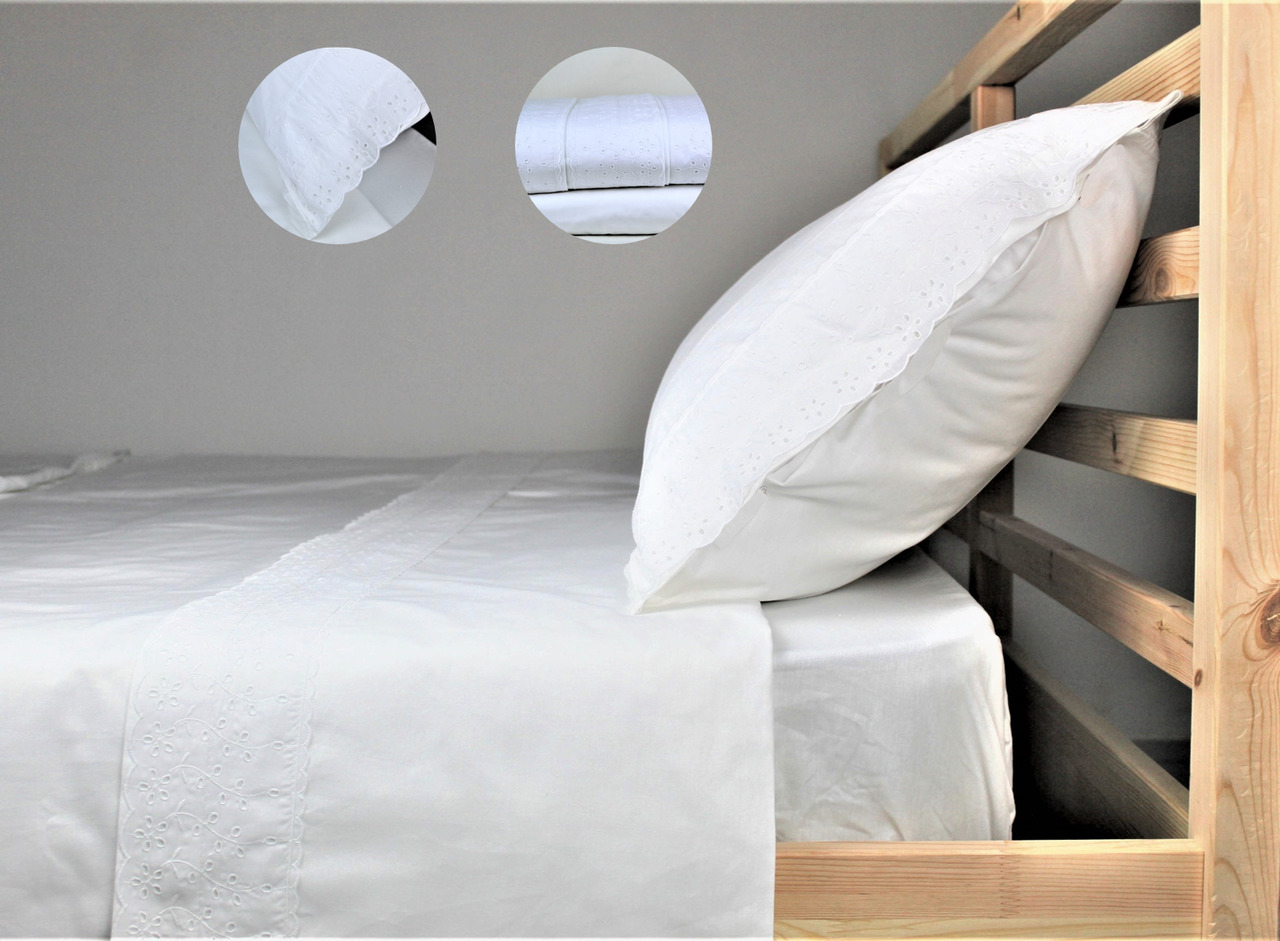 Conjunto de Lençóis Athens Conjunto de roupa de cama branco com bordados florais e estrutura de cama em madeira clara.