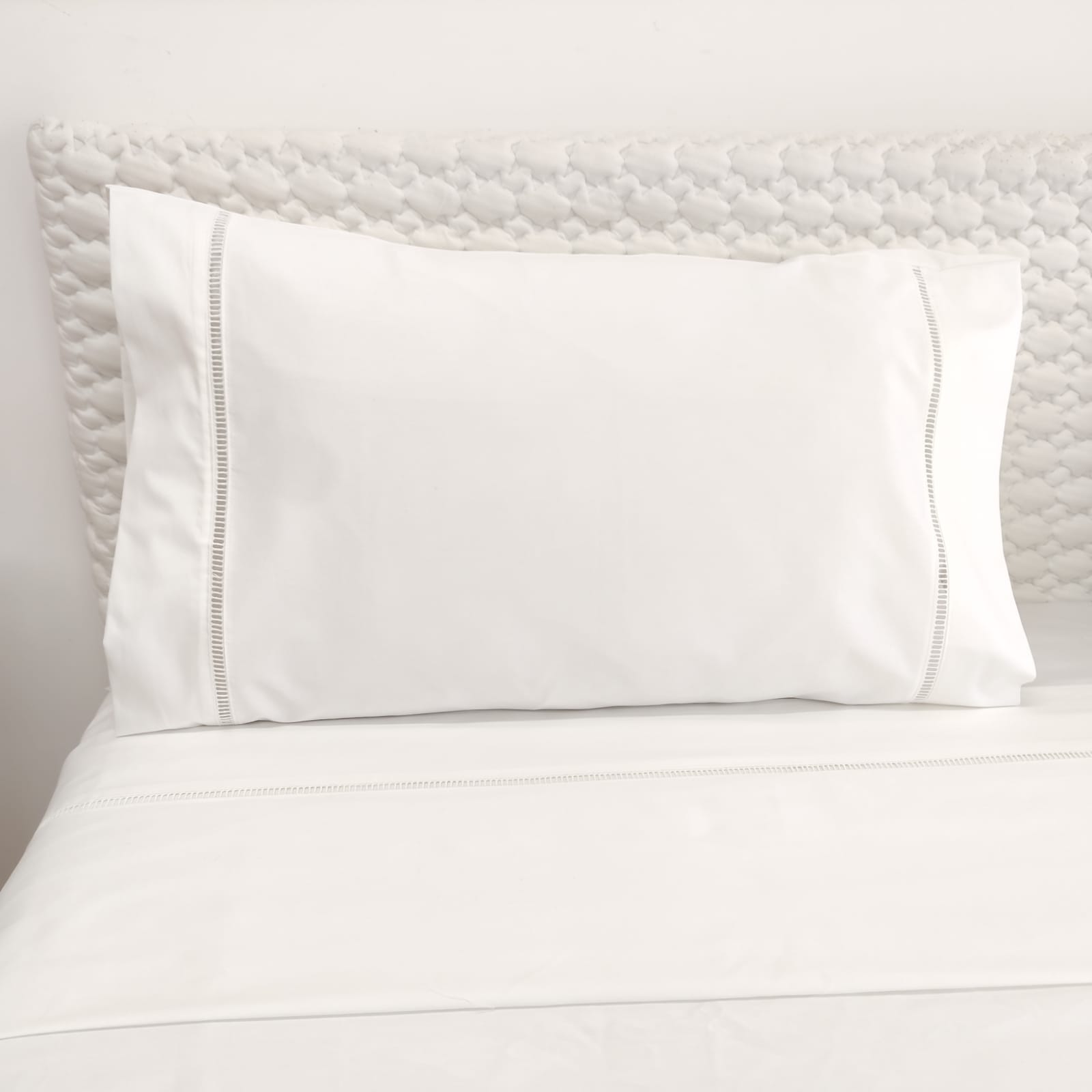Conjunto de Lençóis Escadote Branco Travesseiro branco com fronha decorativa sobre cama com lençóis brancos e cabeceira texturizada