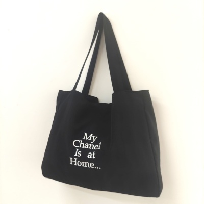 Tote bag preta com texto branco pendurada na parede
