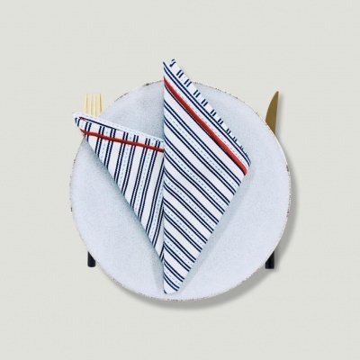 Prato branco com guardanapo riscado e talheres dourados