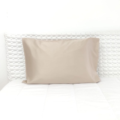 Almofada bege sobre colchão branco com cabeceira estofada branca