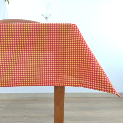 Toalha de mesa xadrez em tons quentes sobre mesa de madeira com copo de vidro