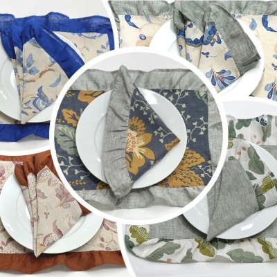 Conjuntos de guardanapos e porta-guardanapos coloridos com padrões florais em pratos brancos.