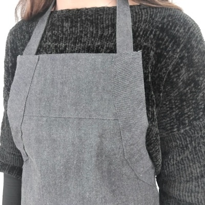 Pessoa a usar avental cinzento por cima de camisola preta texturada
