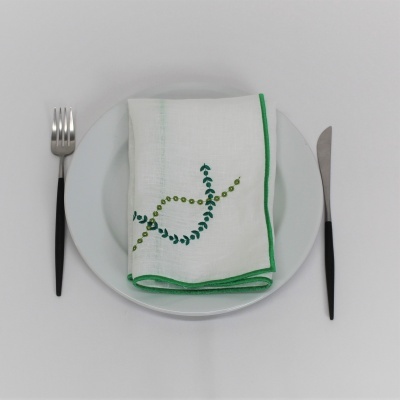 Guardanapo branco bordado com prato branco, garfo e faca com cabos pretos