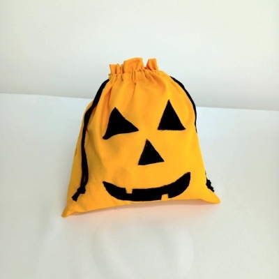 Saco amarelo com rosto de abóbora preto em fundo branco