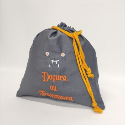 Saco cinzento com cordão amarelo e bordado laranja 'Doçura ou Travessura'.