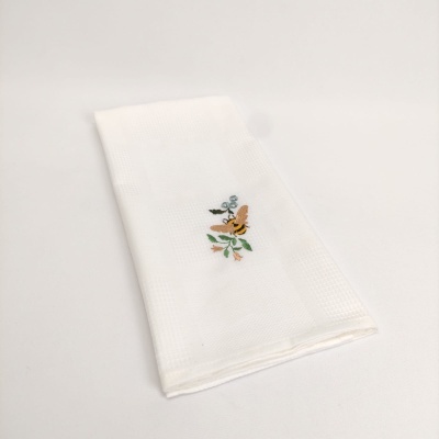 Toalha branca com bordado de flores e folhas.