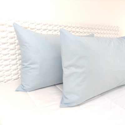 Duas almofadas retangulares azuis sobre superfície branca com cabeceira trançada