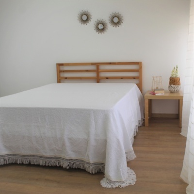 Cama de madeira com edredão branco e mesa de cabeceira decorada