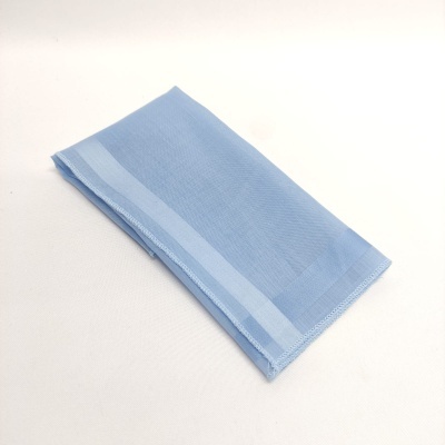 Toalha azul claro com faixas mais claras, dobrada sobre fundo branco