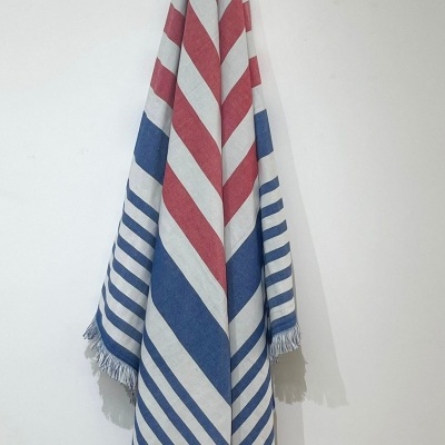 Toalha com riscas vermelhas, brancas e azuis pendurada numa parede branca.