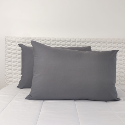Três almofadas cinzentas sobre colchão branco com cabeceira branca acolchoada