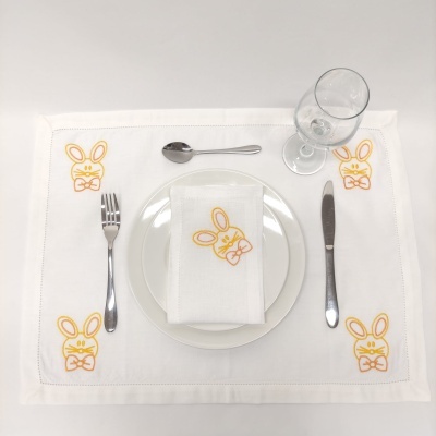 Jogo americano branco com bordados de coelhos amarelos, guardanapo, prato, talheres e copo de vidro