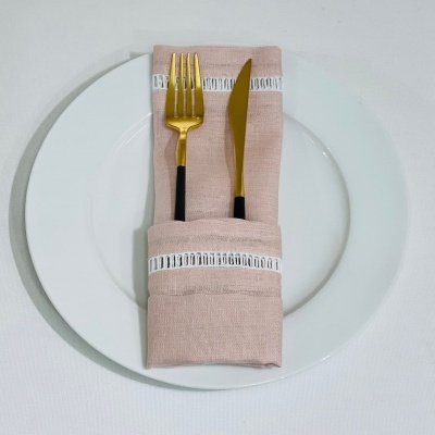 Prato branco com guardanapo rosa e talheres dourados com cabos pretos